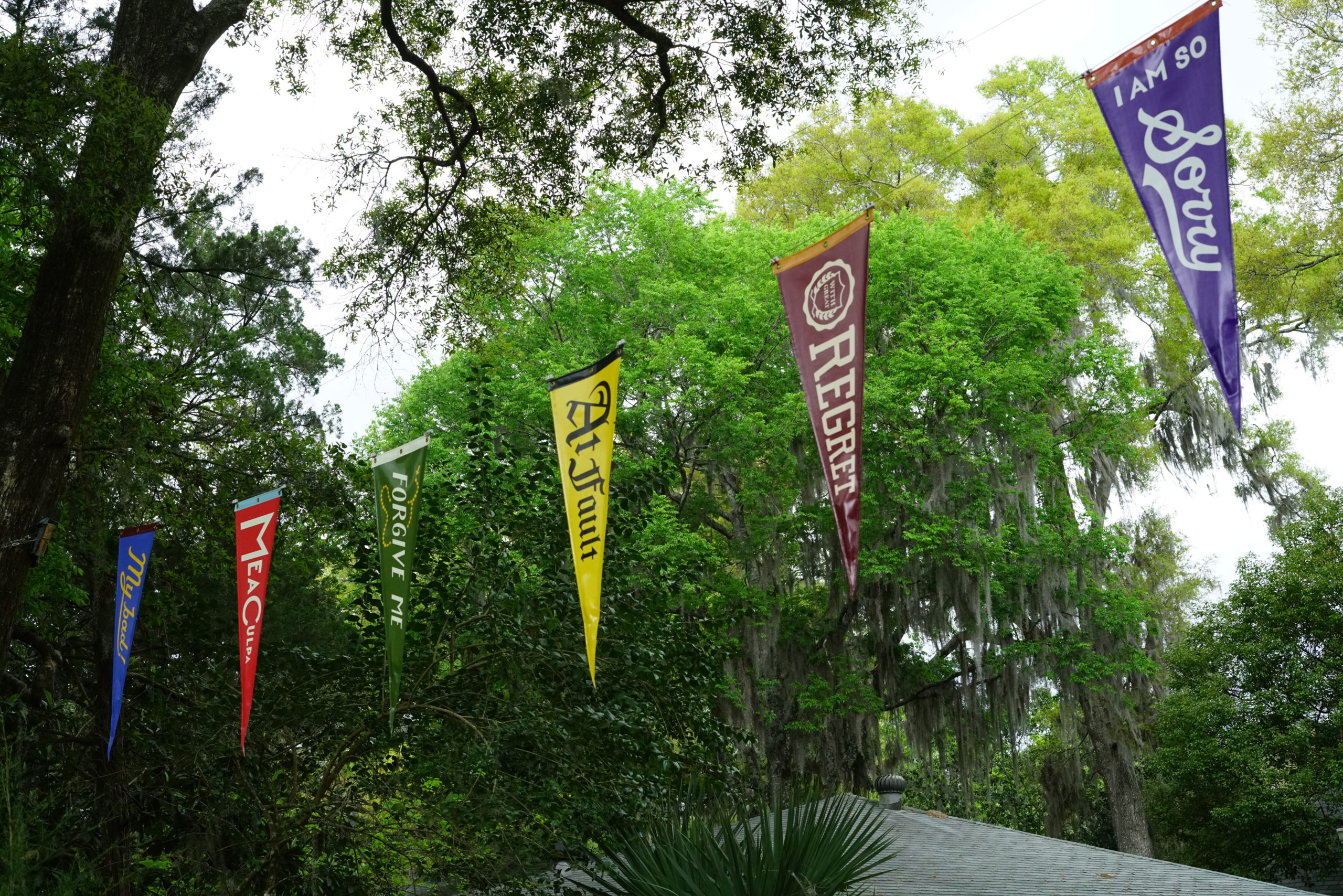 pennants hanging outside in a lush setting, there are 6 colorful pennants