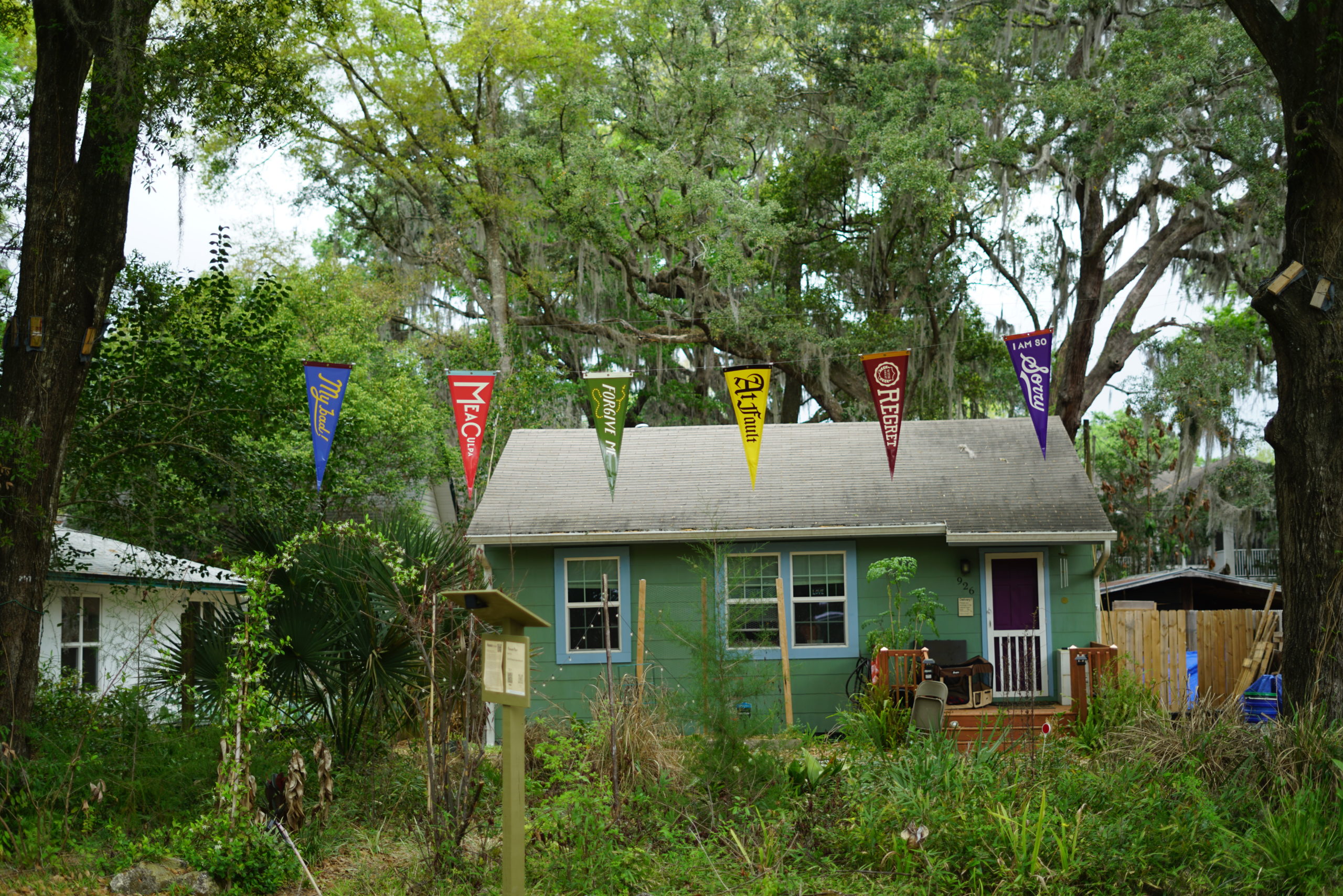 pennants hanging outside in a lush setting with a green house in the background